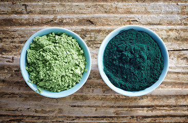 Image showing bowl of spirulina algae powder and wheat sprout powder on wooden