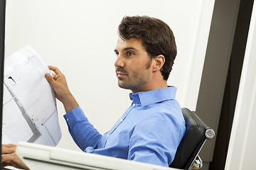 Image showing Young man reading written agreements for work