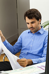 Image showing Young man reading written agreements for work