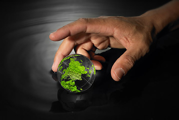 Image showing Hand reaching for crystal earth ball