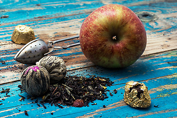 Image showing tea leaves and red apple on wooden background