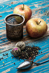 Image showing tea leaves and red apple on wooden background