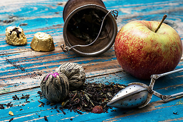 Image showing tea leaves and red apple on wooden background