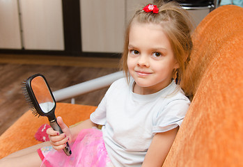 Image showing Little girl with a mirror sits on the couch