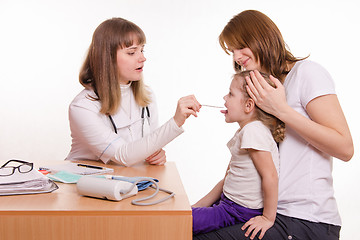 Image showing Pediatrician looking into the throat of the child sitting on the lap of mother