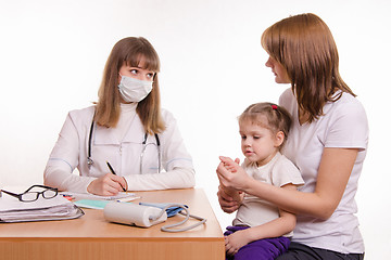 Image showing Pediatrician talking in office with a young mother with child on her lap