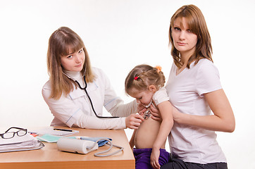 Image showing Pediatrician examining a child in the arms of mother