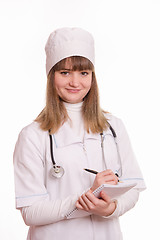 Image showing Medical officer in a white coat writes in a notebook information