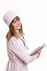 Image showing Health worker in a white coat, hat stands with documents in hand and smiling