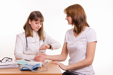 Image showing Physician at the table checks the pulse of a patient