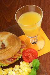 Image showing Bacon and cheese bagel with scrambled eggs and juice