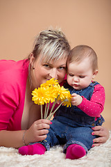 Image showing infant baby with his mom and yellow flowers