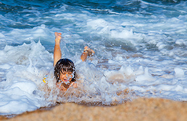 Image showing Little boy laughing in the foam of waves at sea