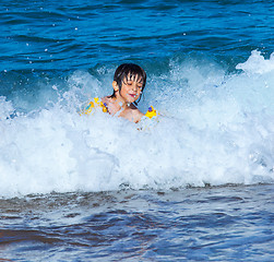 Image showing Little boy laughing in the foam of waves at sea