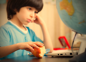 Image showing boy sitting with a laptop and eating apple