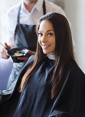 Image showing happy young woman coloring hair at salon