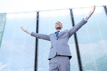 Image showing young smiling businessman over office building