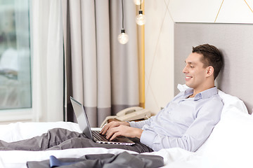 Image showing happy businesswoman with laptop in hotel room