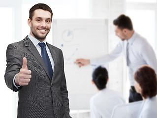 Image showing handsome buisnessman showing thumbs up in office