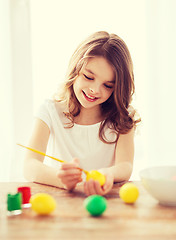 Image showing smiling little girl coloring eggs for easter