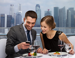 Image showing smiling couple with smartphone at restaurant