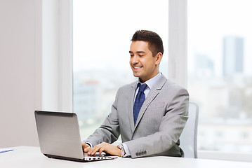 Image showing happy businessman working with laptop in office