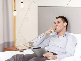 Image showing businessman with tablet pc and phone in hotel room