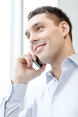 Image showing smiling businessman with smartphone in office