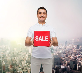 Image showing smiling man with sale sigh up over city background