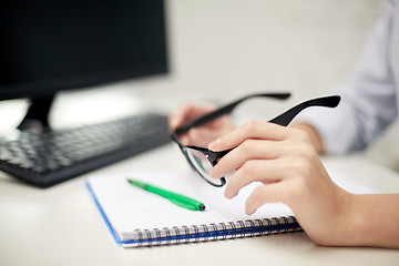 Image showing close up of hands with eyeglasses and notebook