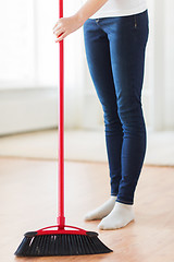 Image showing close up of woman legs with broom sweeping floor