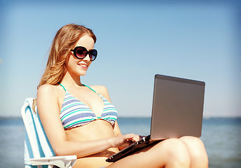Image showing girl looking at tablet pc on the beach