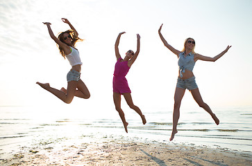Image showing happy female friends dancing and jumping on beach