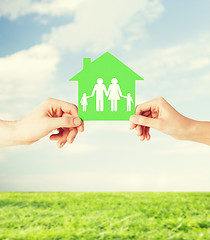 Image showing hands holding green house with family