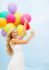 Image showing smiling woman with colorful balloons outside