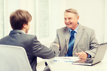 Image showing older man and young man shaking hands in office