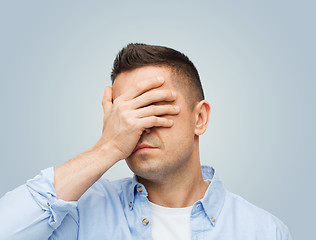 Image showing unhappy man covering his eyes by hand