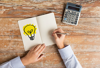 Image showing close up of hands with calculator and notebook