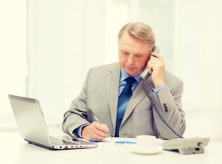 Image showing busy older businessman with laptop and telephone