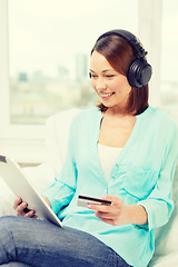 Image showing happy woman with tablet pc and credit card at home