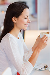 Image showing smiling young woman drinking coffee at cafe