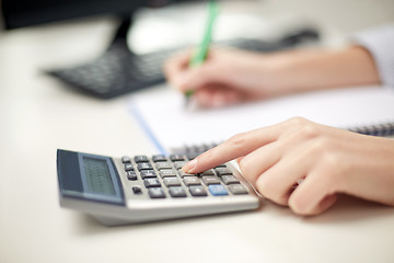 Image showing close up of woman with calculator taking notes