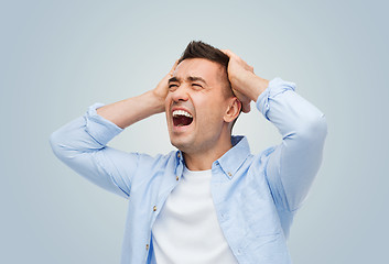 Image showing unhappy man with touching his head and screaming