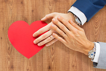 Image showing close up of male gay couple hands with red heart