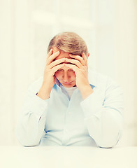 Image showing stressed old man holding head at home