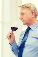 Image showing older man smelling red wine