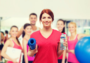 Image showing smiling girl with bottle of water after exercising