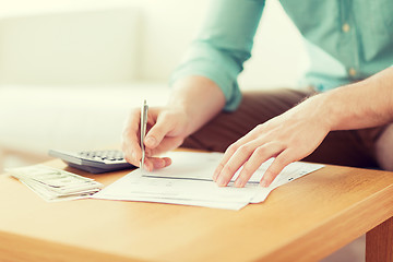 Image showing close up of man counting money and making notes