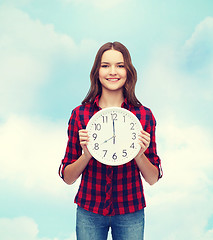 Image showing young woman in casual clothes with wall clock