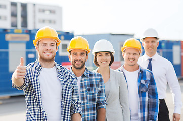 Image showing group of smiling builders in hardhats outdoors